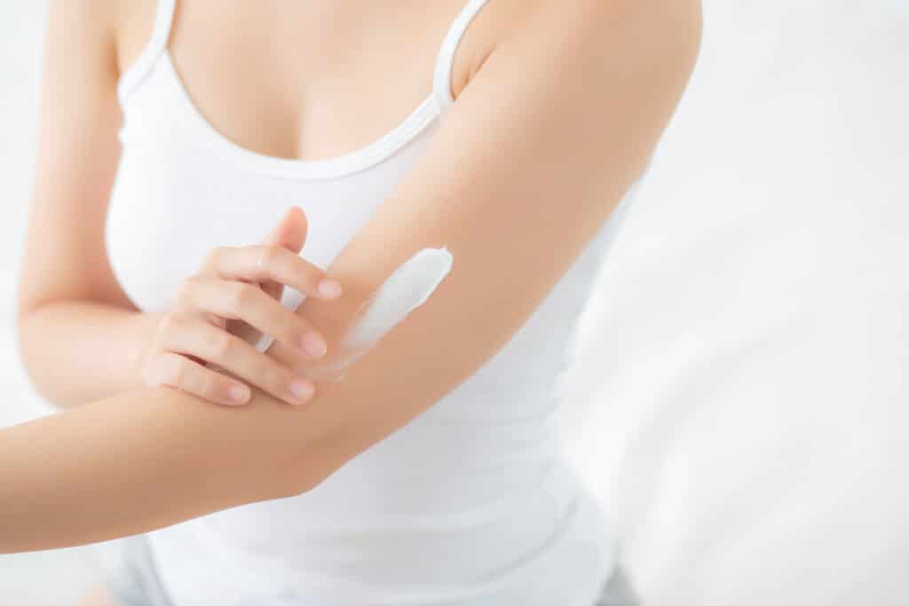 Closeup of a woman applying sunscreen to her arm