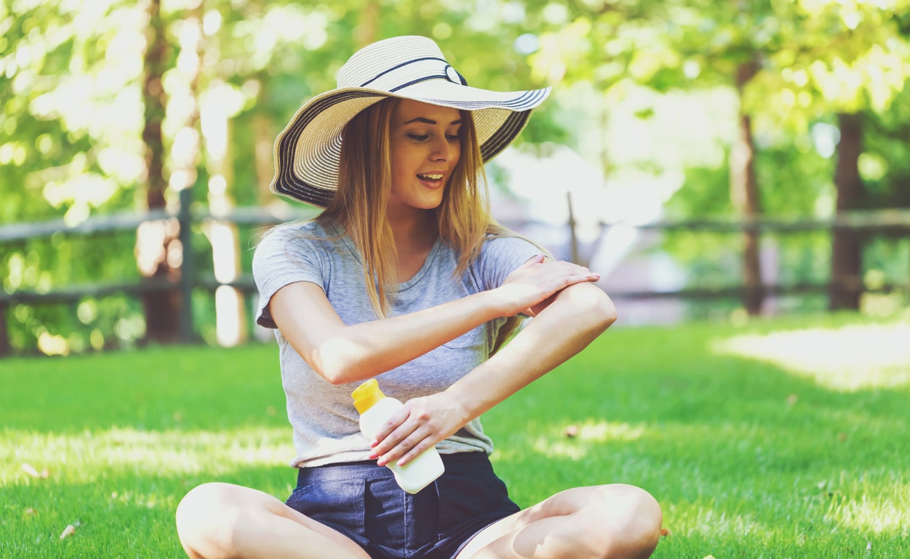 Woman applies sunscreen while at a park