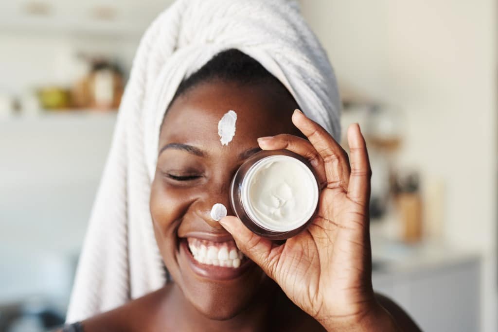 Woman holding a skincare product up to her face
