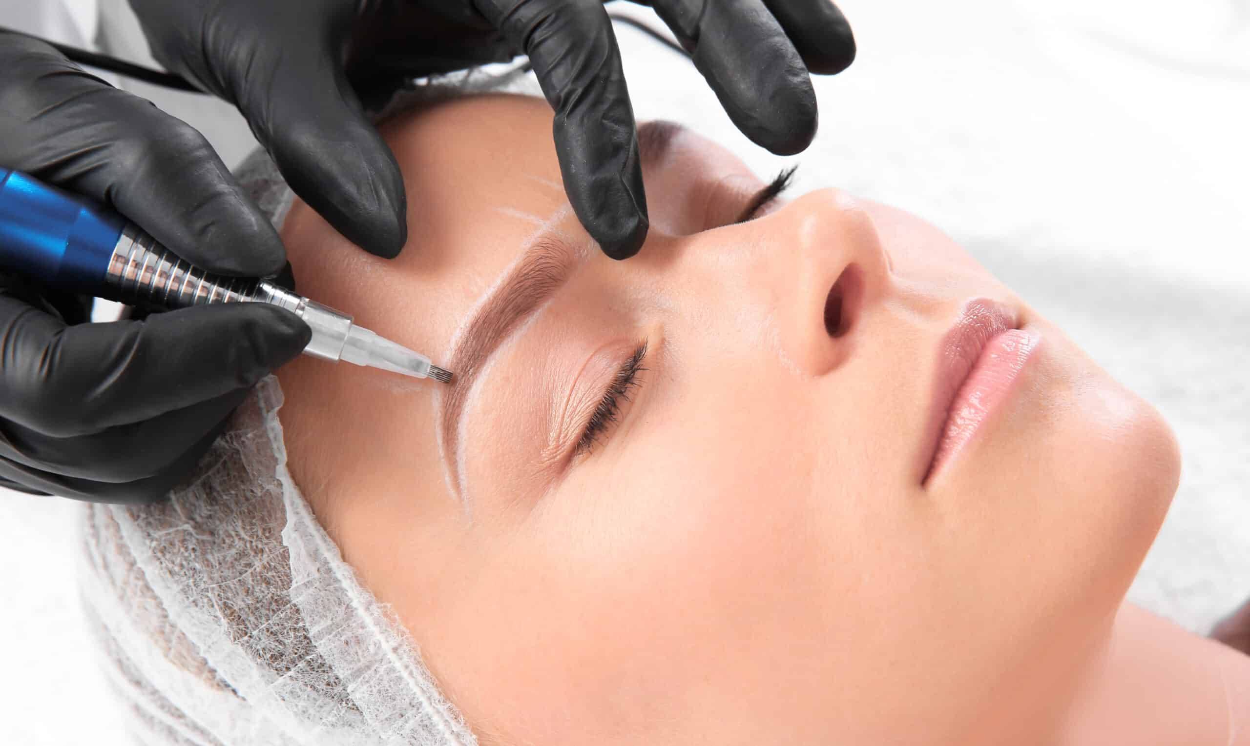 Young woman undergoing eyebrow correction procedure in salon