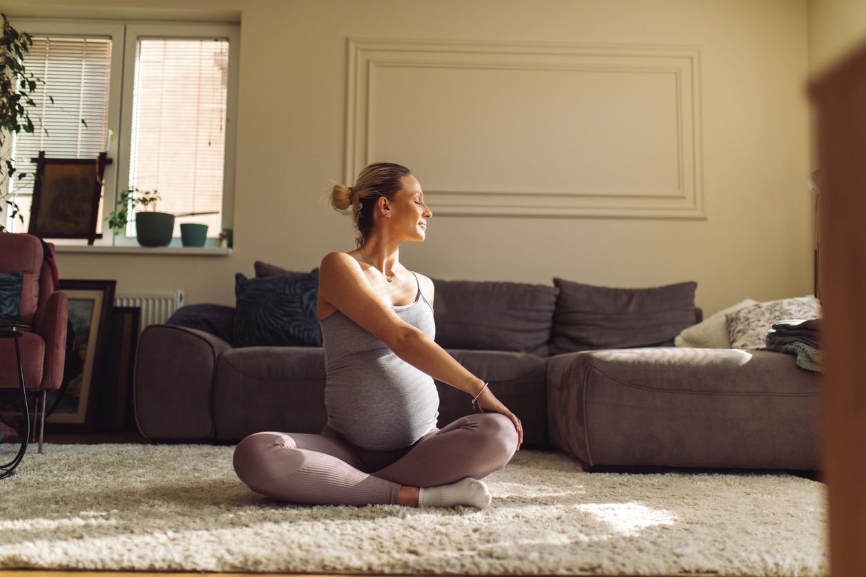 Young pregnant woman doing prenatal yoga at home